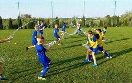 Dzieci na łące polewają się wodą z butelek